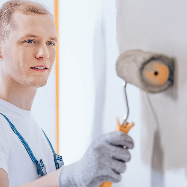 worker paints internal wall gray